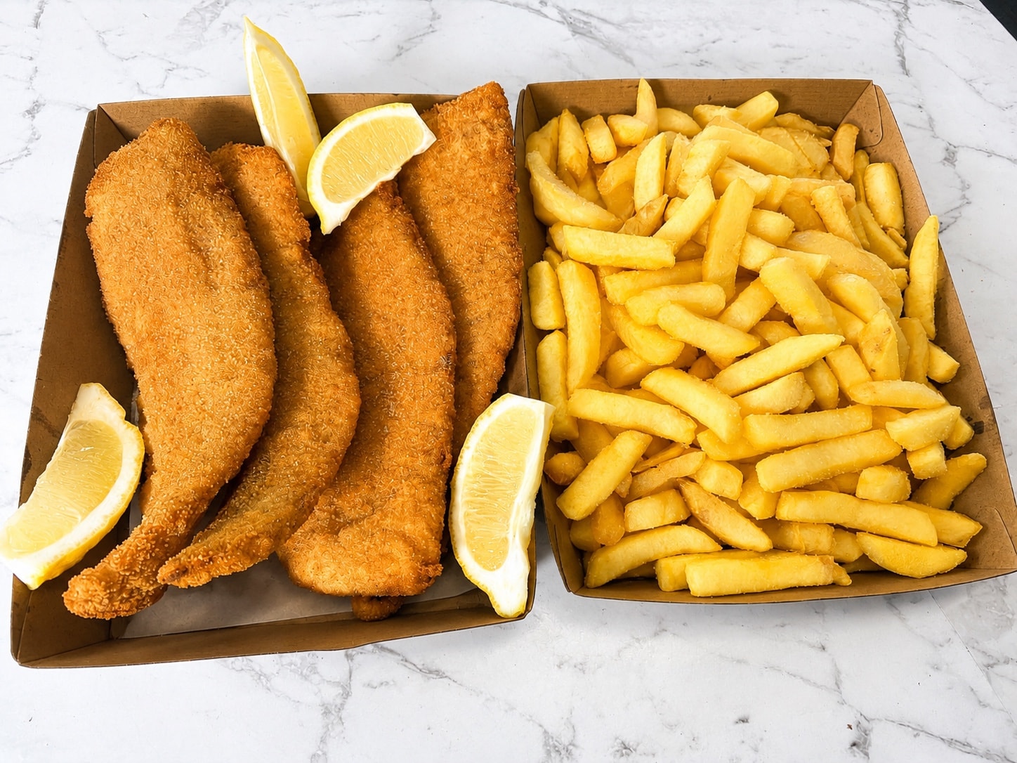 Golden crumbed fish and chips in takeaway boxes